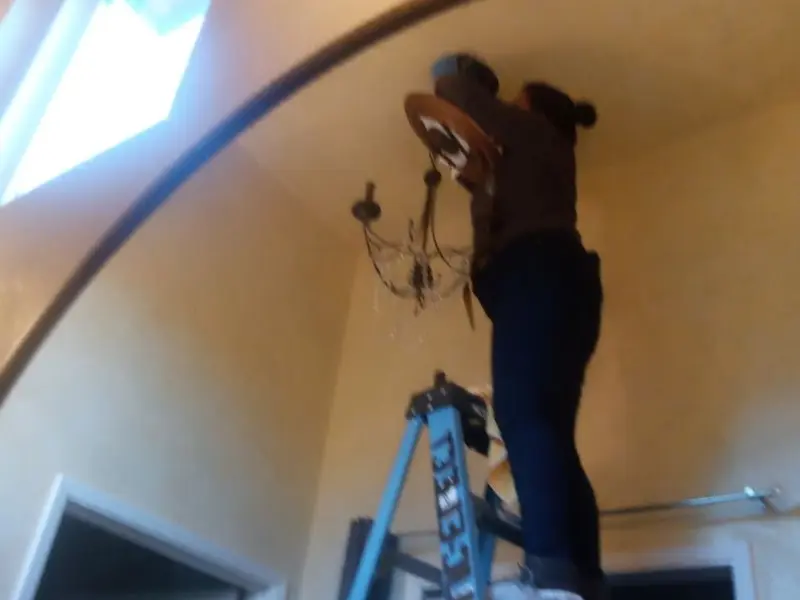 Electrician installing a chandelier in a Bossier City residence